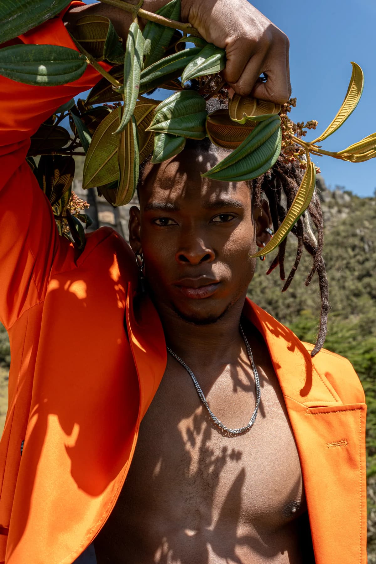 Retrato editorial de moda con traje naranja entre vegetación