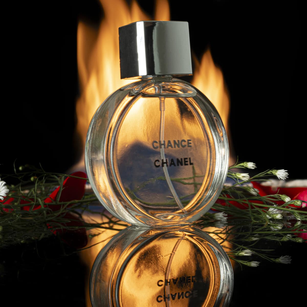 Fotografía de producto de un perfume entre fuego y reflejos
