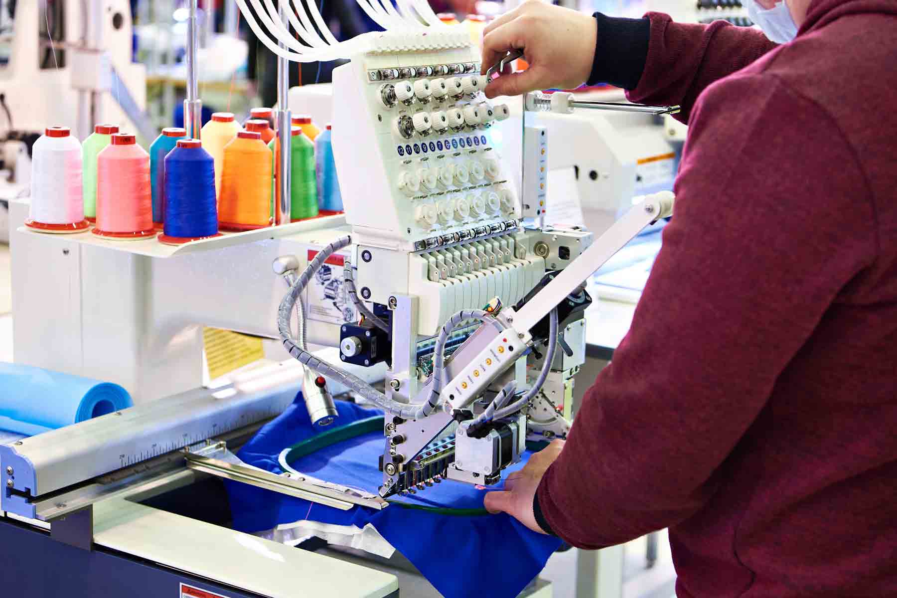 Operaria profesional trabajando en maquina de bordado industrial